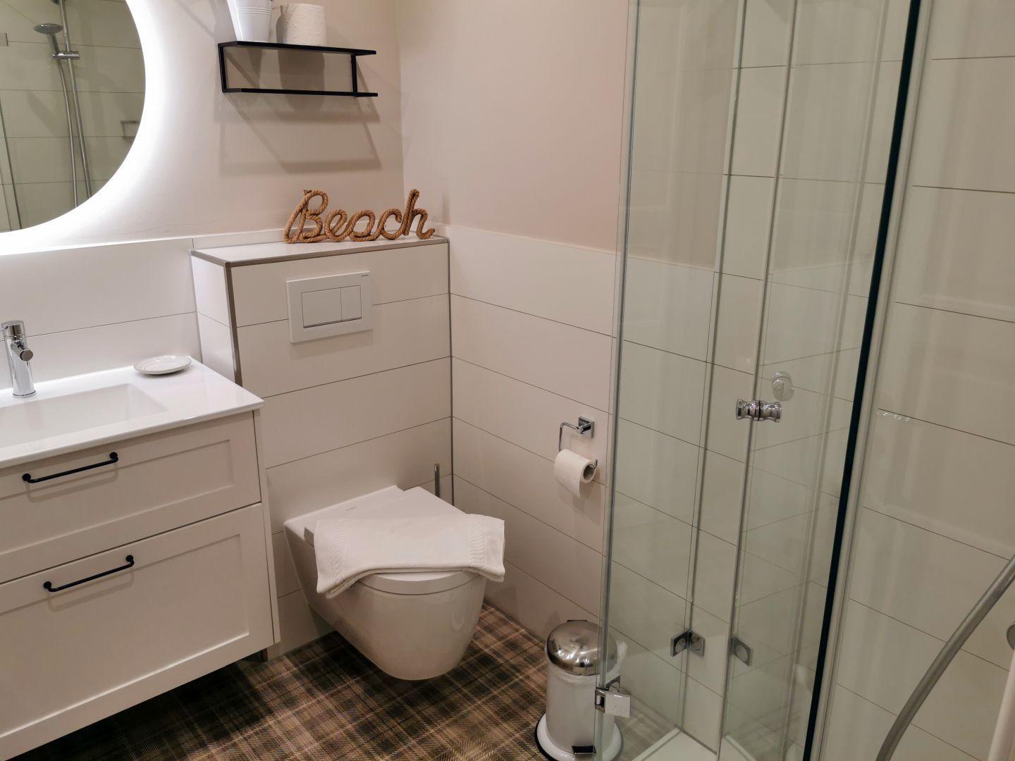 Badezimmer mit Dusche, Toilette und Waschbecken mit Spiegel.