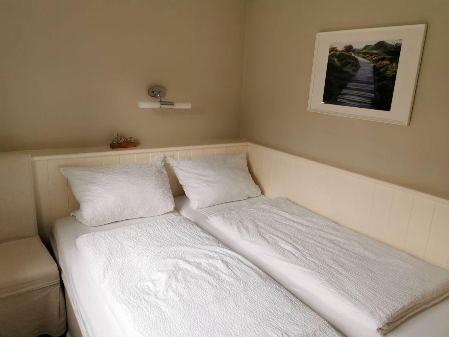 Schlafzimmer mit Doppelbett, weißen Bettwäsche und Wandbild.