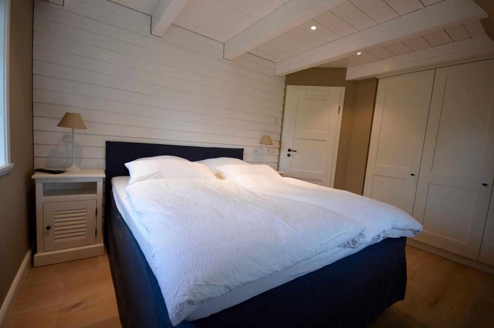 Schlafzimmer mit Doppelbett, weißen Nachttischen und Kleiderschrank.