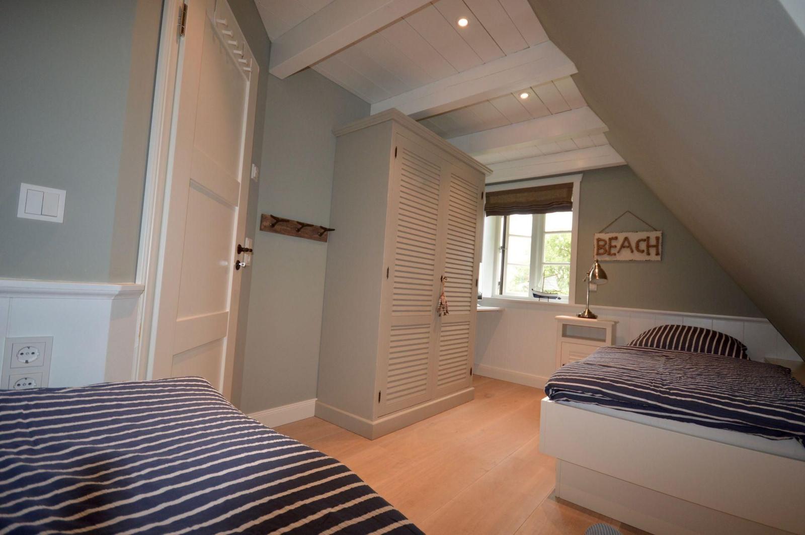 Zimmer mit Dachschrägen, Bett, Kleiderschrank und Fenster mit Blick.