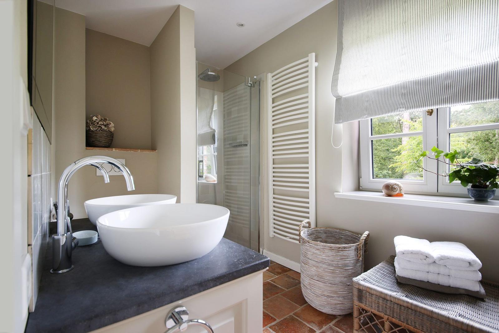 Badezimmer mit zwei Waschbecken, Dusche und Fenster mit Pflanze.