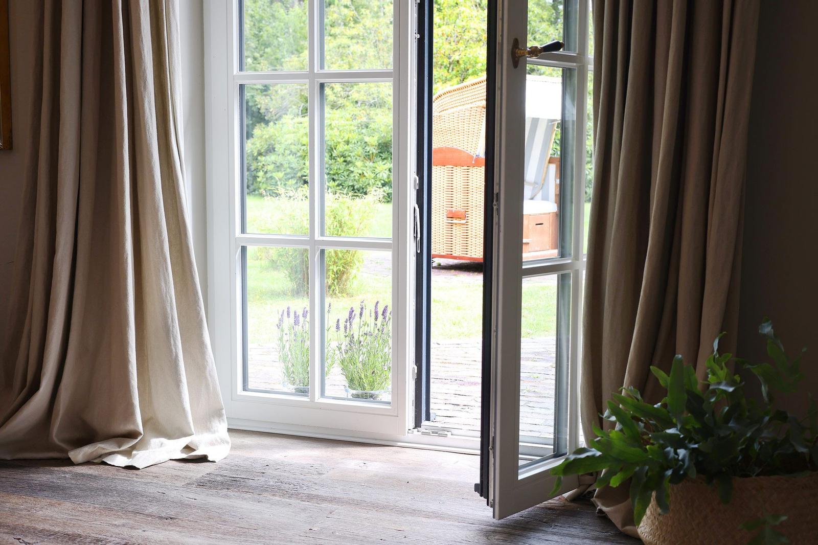 Durch offene Fensterblick auf Garten mit Lavendel und Holzterrasse