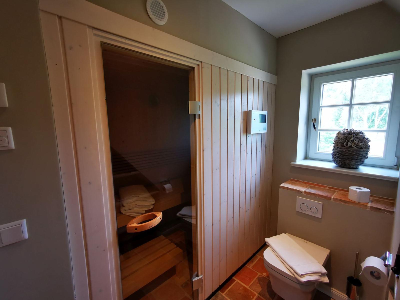 Sauna mit Holzwand, Toilette und Fenster mit Blumenkorb.