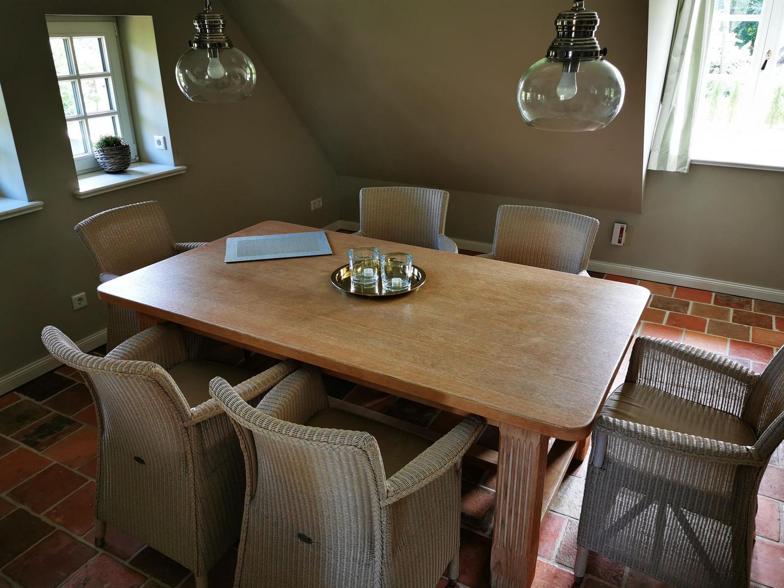 Esszimmer mit Holztisch, sechs Stühlen und zwei Deckenleuchten.