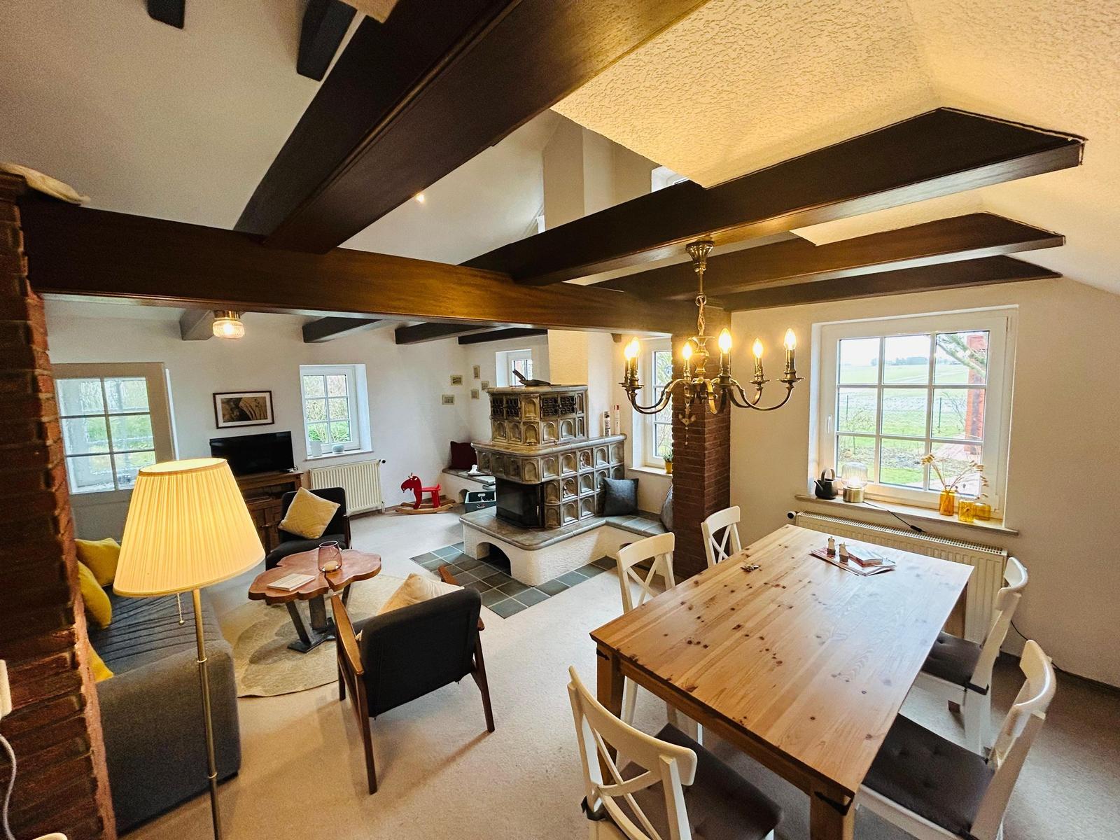 Wohn- und Essbereich mit Kamin, Holztisch und Balken.