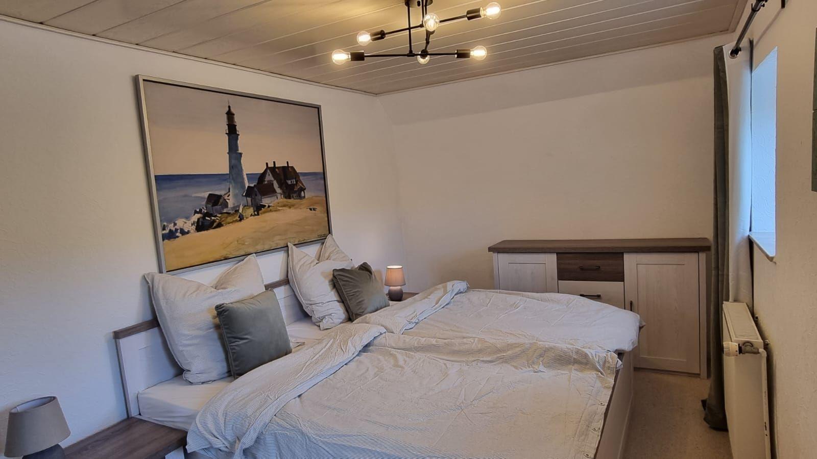 Schlafzimmer mit Bett, Wandbild und Schrank.