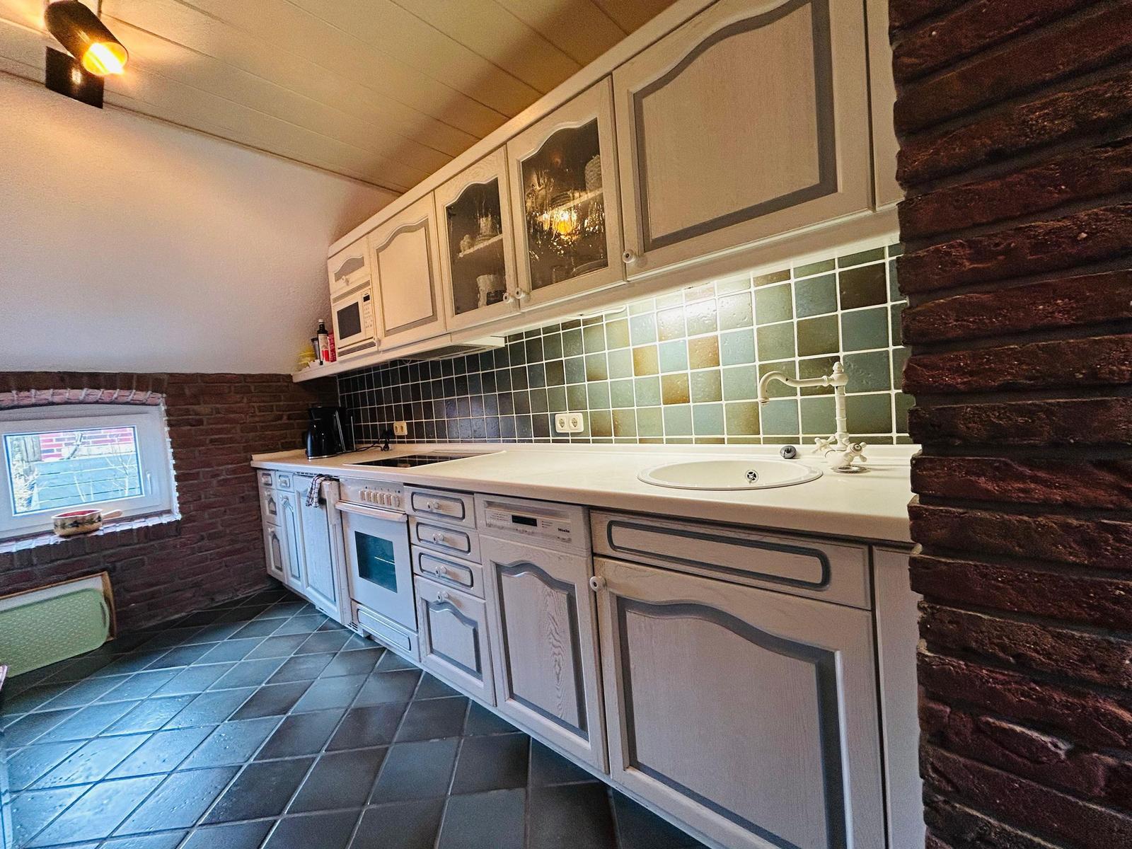 Küche mit weißen Schränken, Backofen und Waschbecken