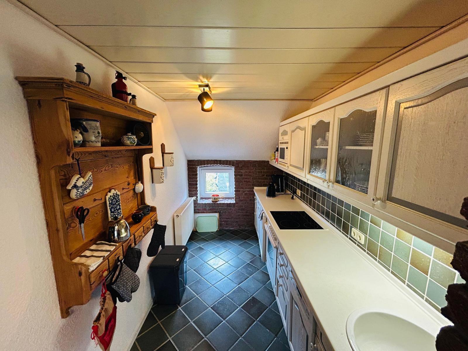 Küche mit Holzregal, Arbeitsplatte und Fenster