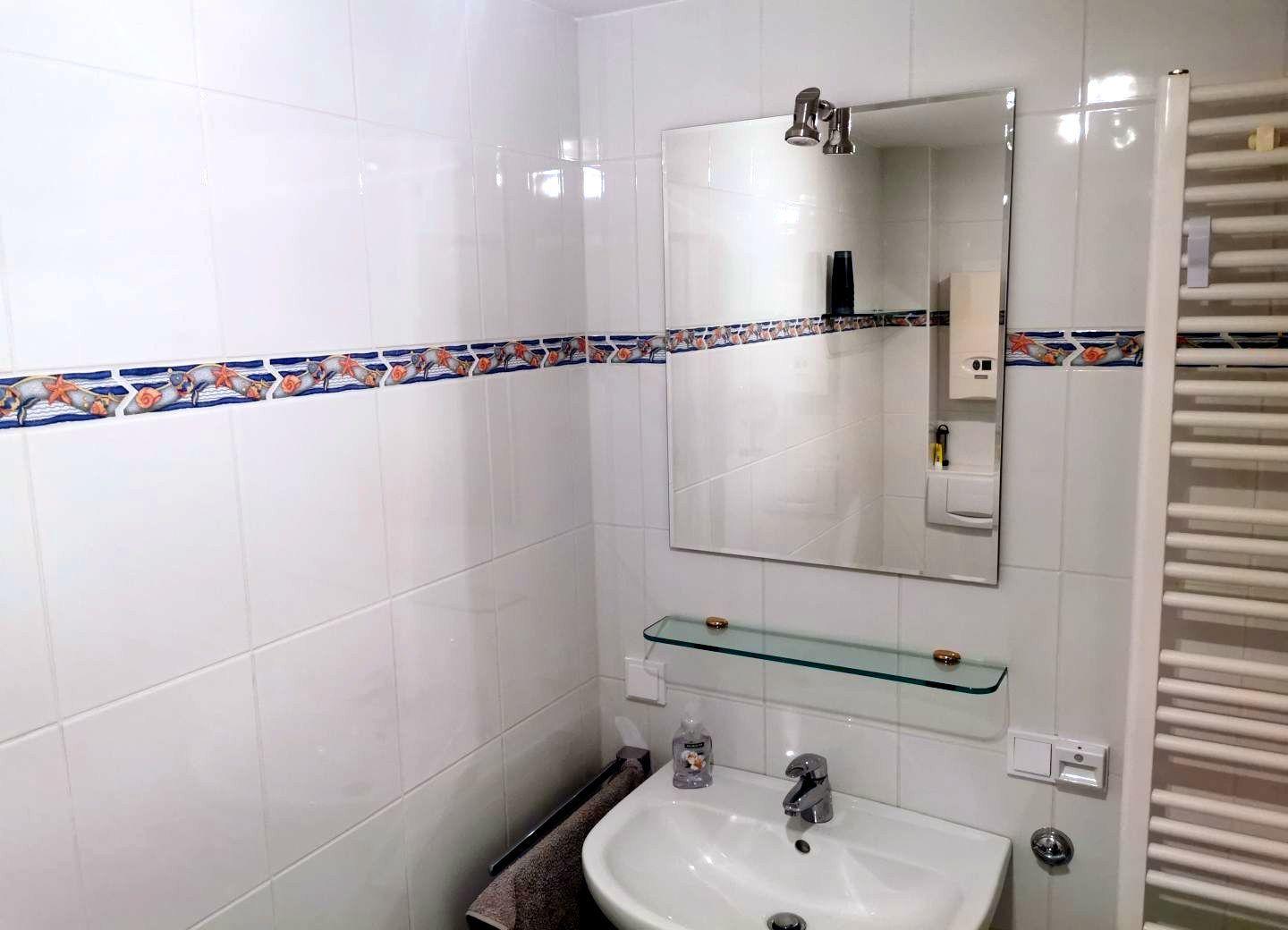 Badezimmer mit Waschbecken, Spiegel und Heizkörper