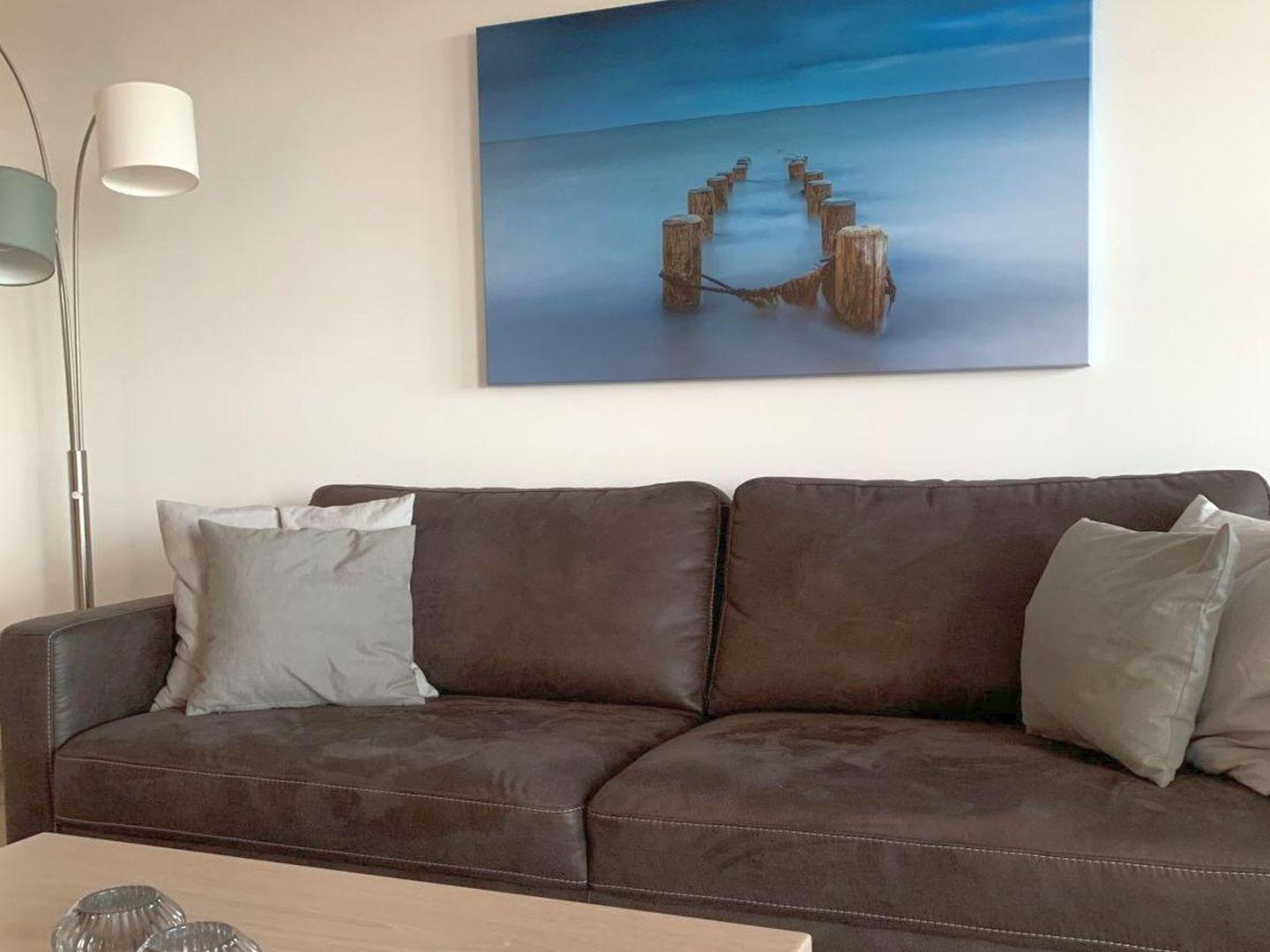 Ein braunes Sofa mit Kissen und einer Wanddekoration über dem Sofa.