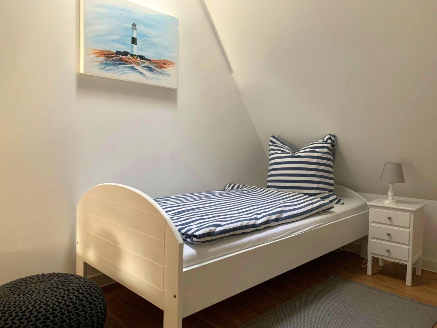Ein Schlafzimmer mit einem Bett, Nachttisch und Wandbild.