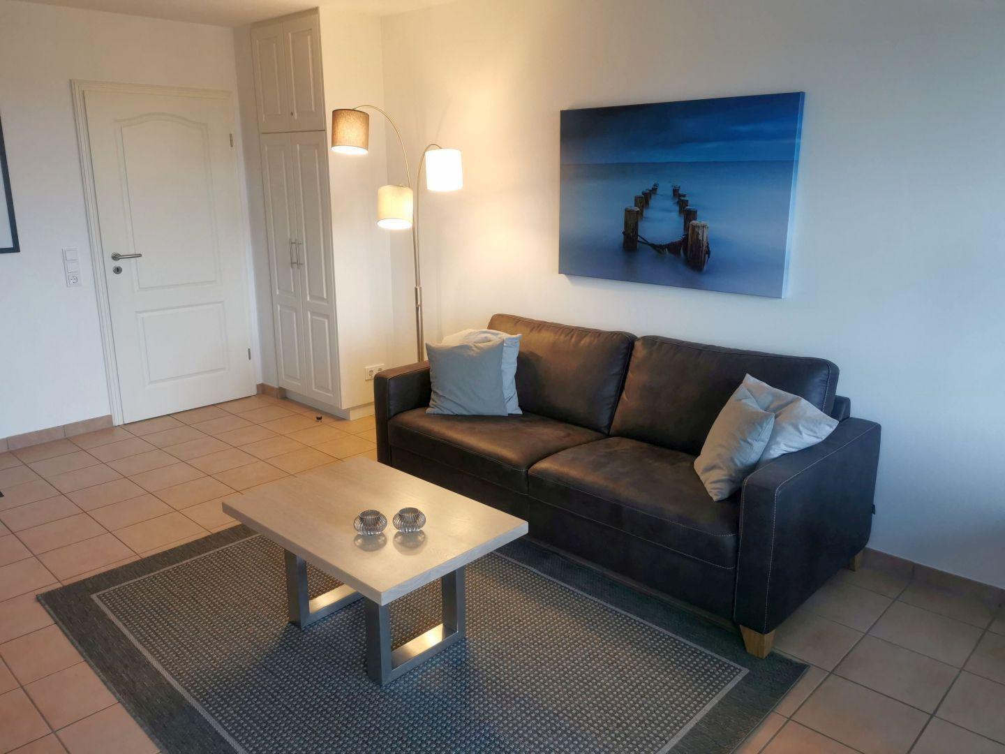Wohnzimmer mit Sofa, Couchtisch und Wandbild.