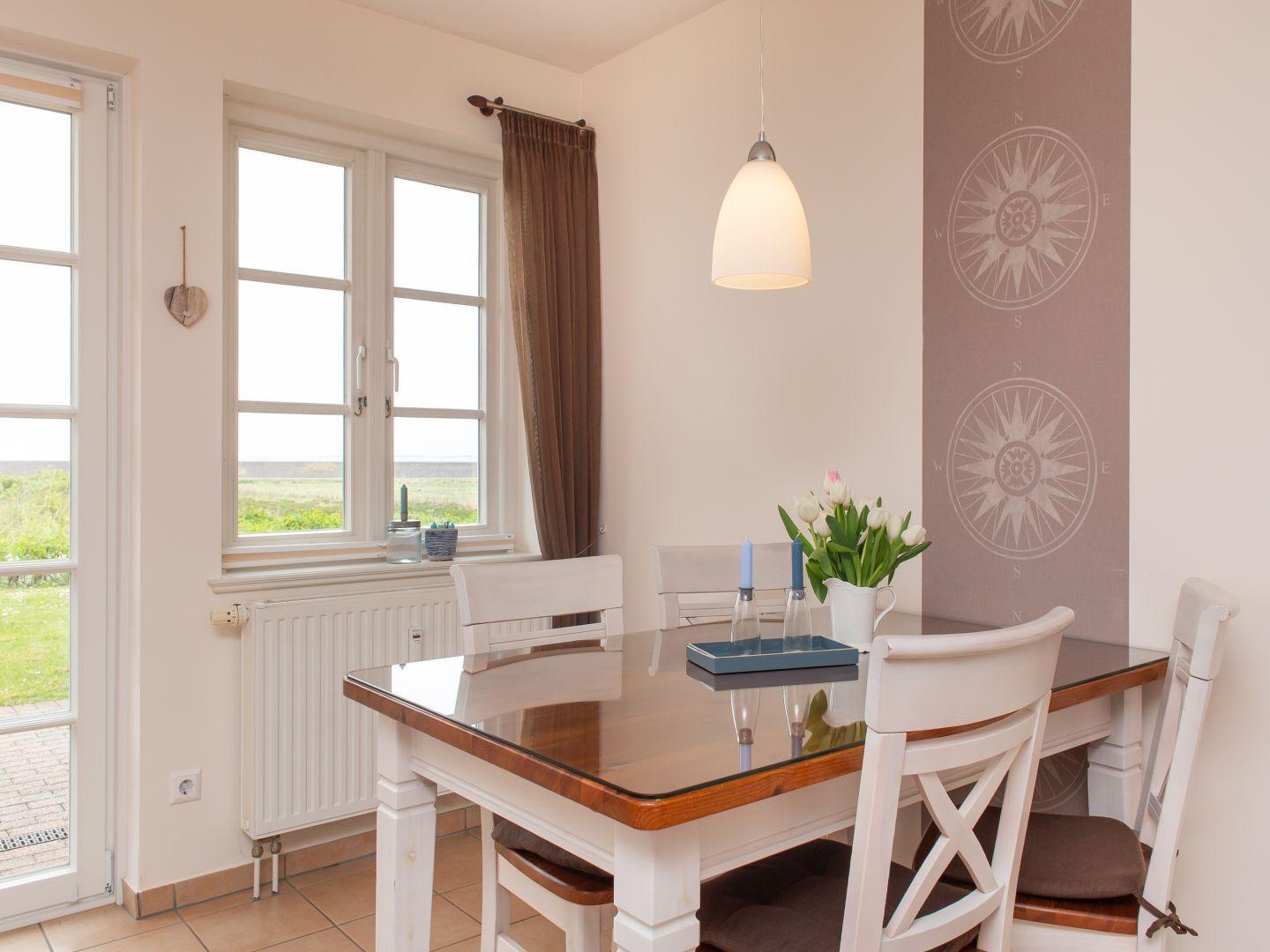 Esszimmer mit Tisch, Stühlen und Fensterblick auf Grünland.