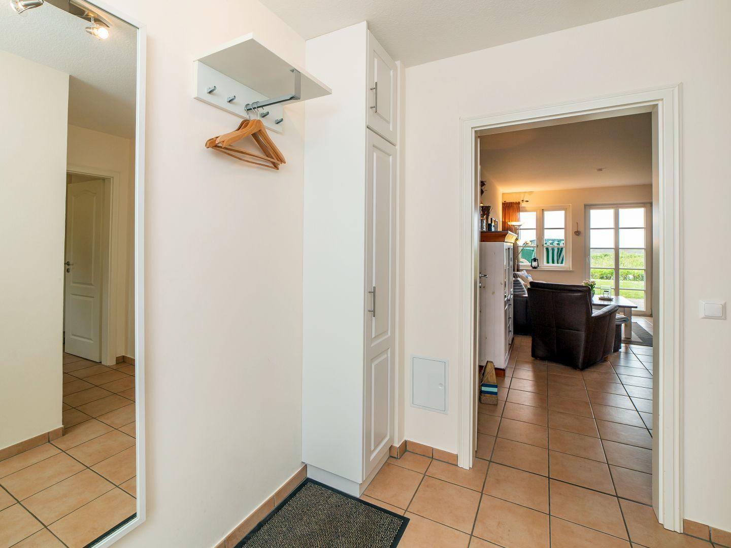 Hausflur mit Kleiderhaken, Schrank und Blick in Wohnzimmer.