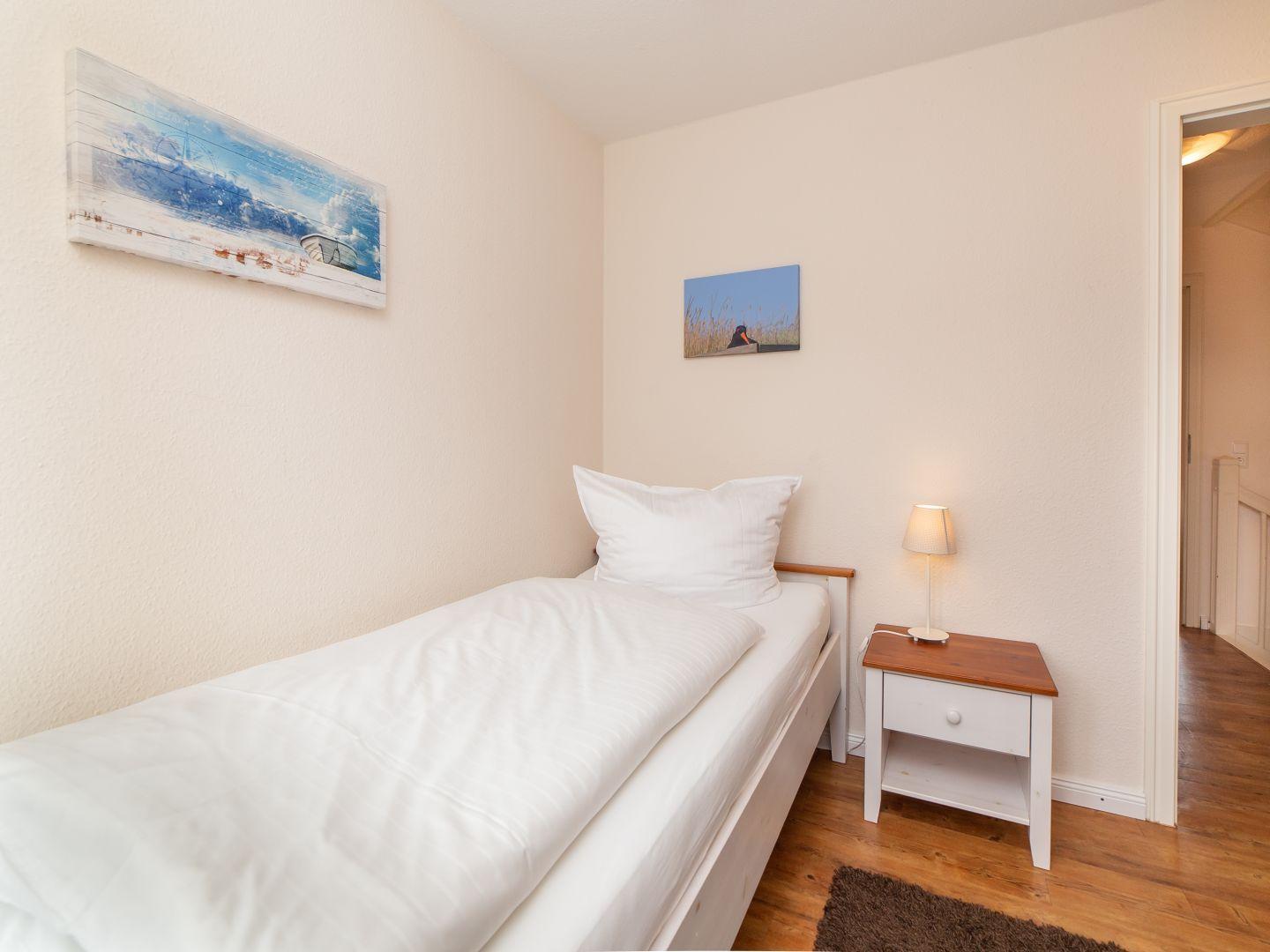 Ein Schlafzimmer mit einem Bett, Nachttisch und Wandbildern.
