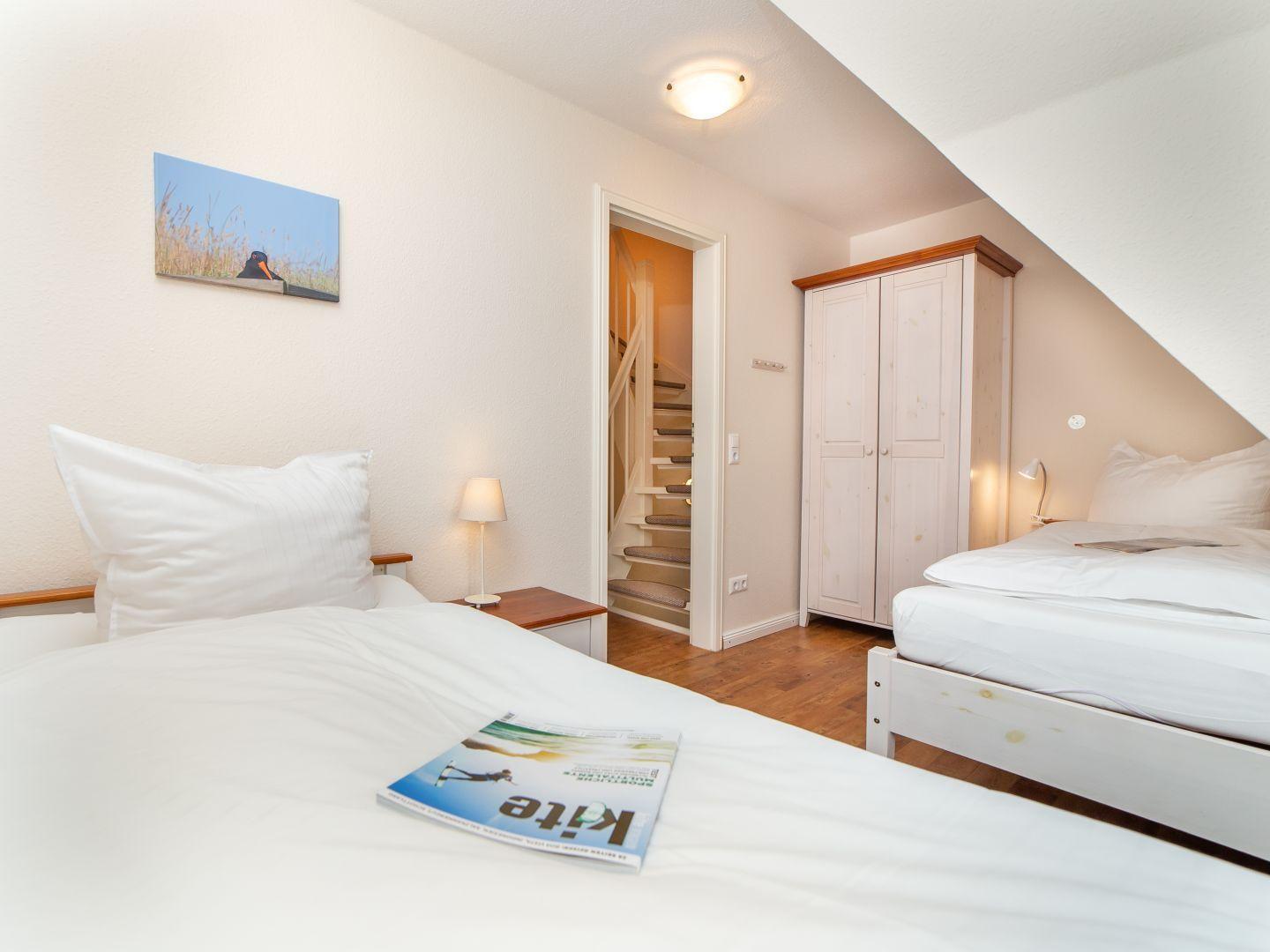 Zwei Betten, Kleiderschrank und Treppe zur Unterkunft.