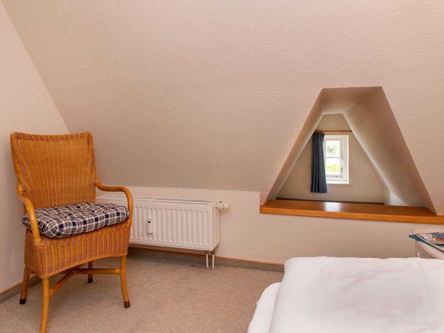 Schlafzimmer mit Dachschrägen, Stuhl und Fenster