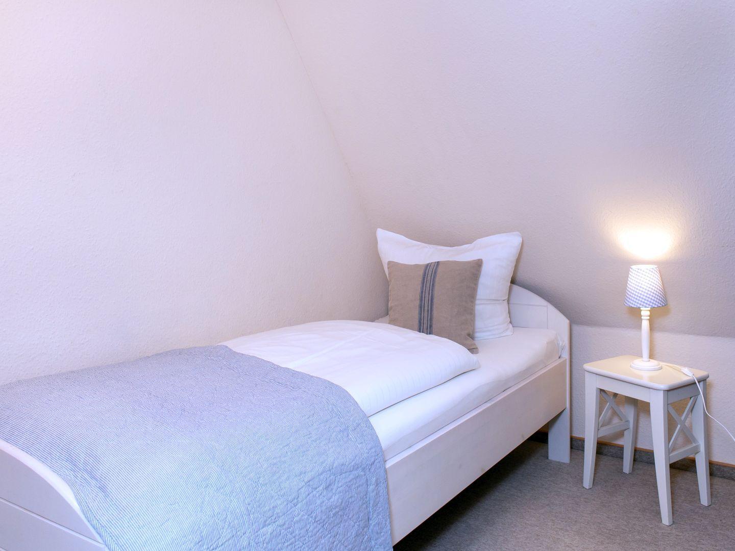 Ein Schlafzimmer mit einem Bett, einem Nachttisch und einer Lampe.