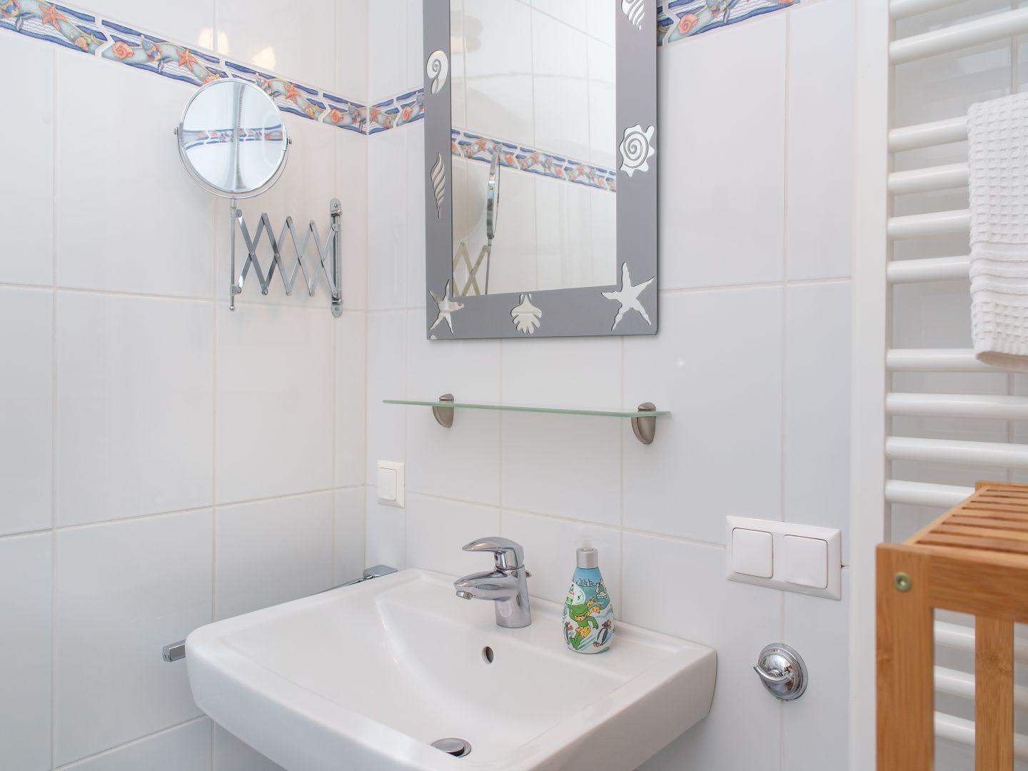 Badezimmer mit Waschbecken, Spiegel und Heizkörper
