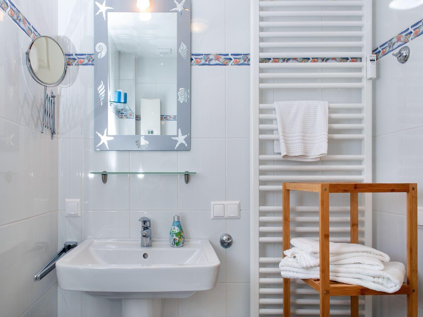 Badezimmer mit Spiegel, Waschbecken und Handtuchhalter.