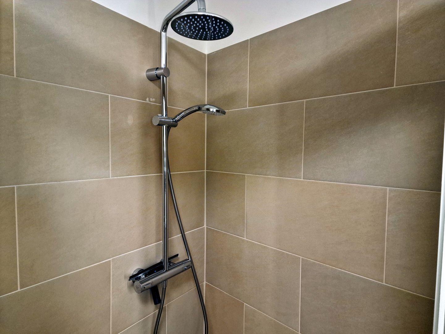 Dusche mit Duschbrause und Handbrause an der Wand