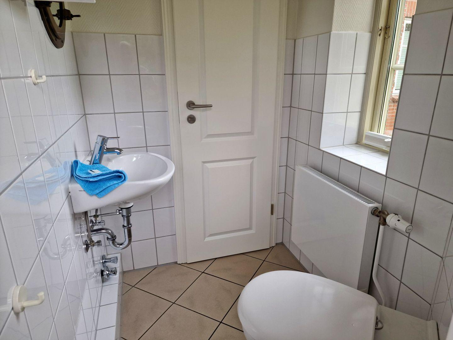 Badezimmer mit Waschbecken, Toilette und Fenster