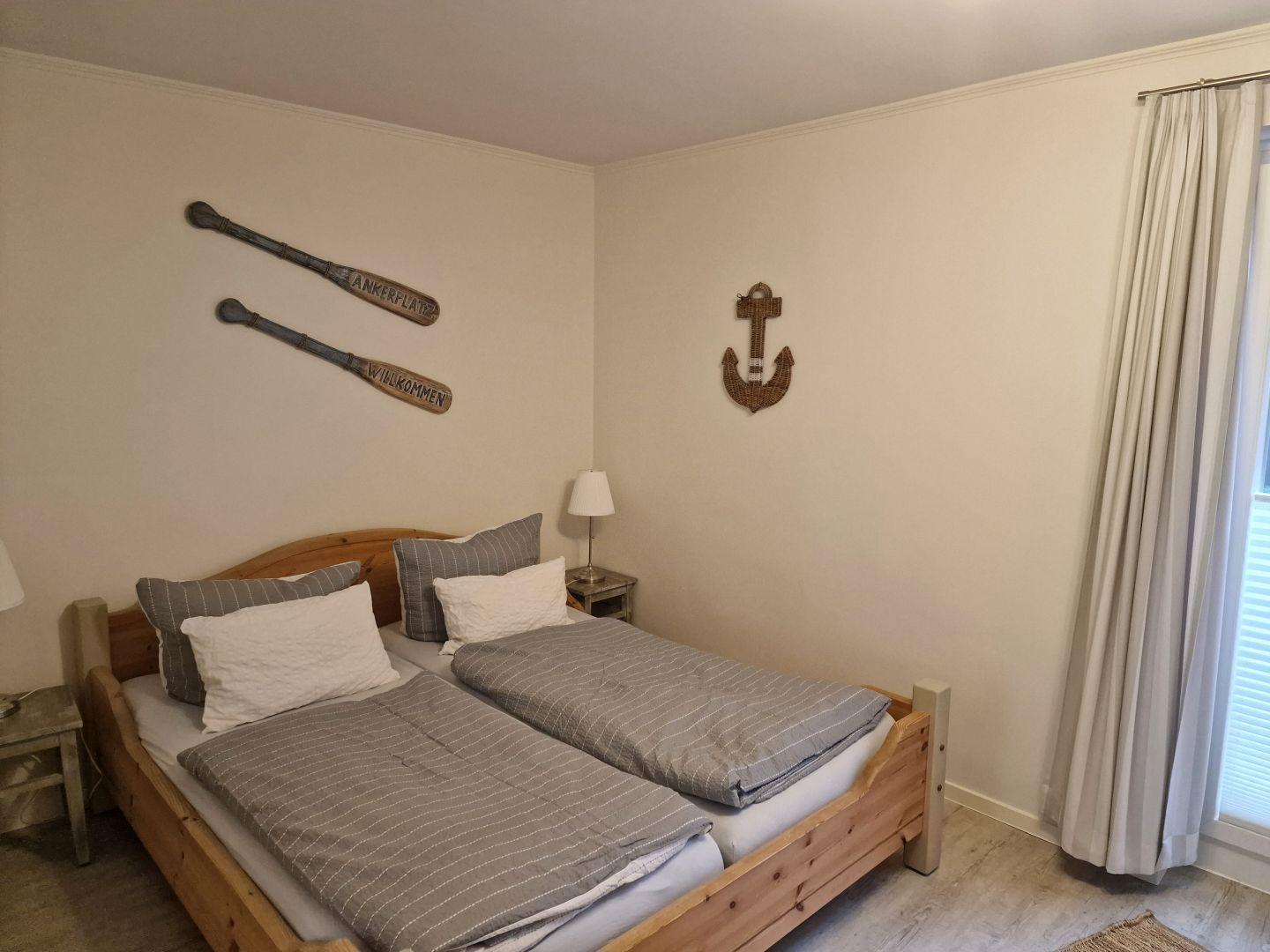 Doppelbett mit Holzrahmen, Wanddekoration mit Ruder und Anker, Nachttisch mit Lampe.
