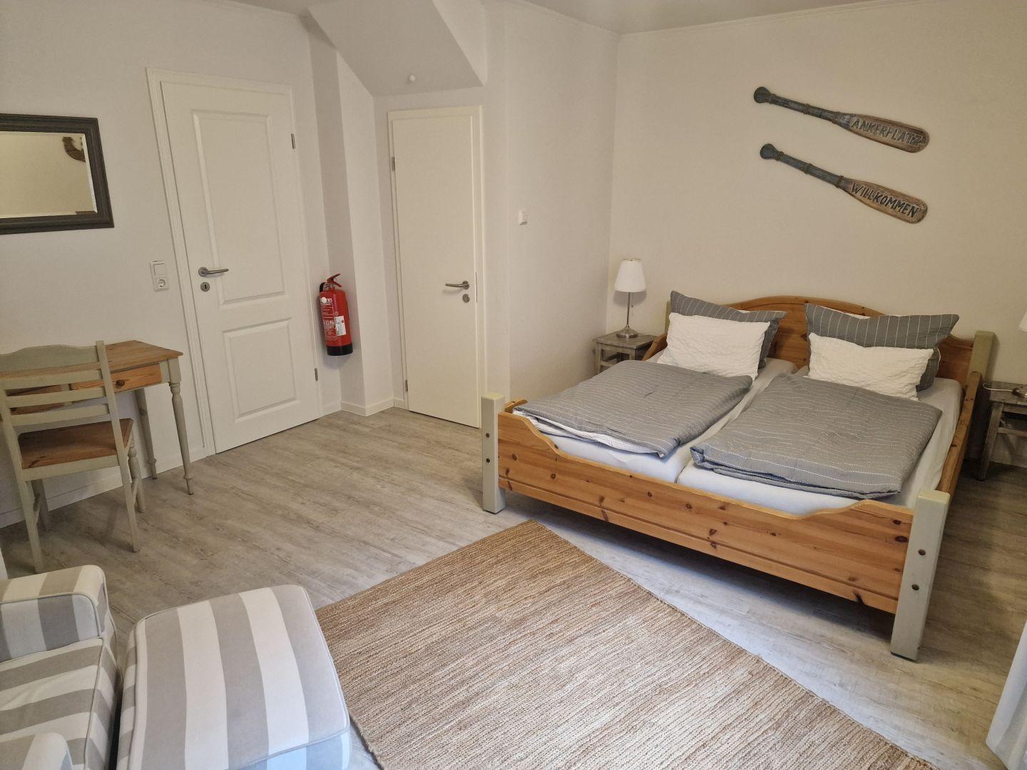 Schlafzimmer mit Doppelbett, Schreibtisch und Wanddekoration.