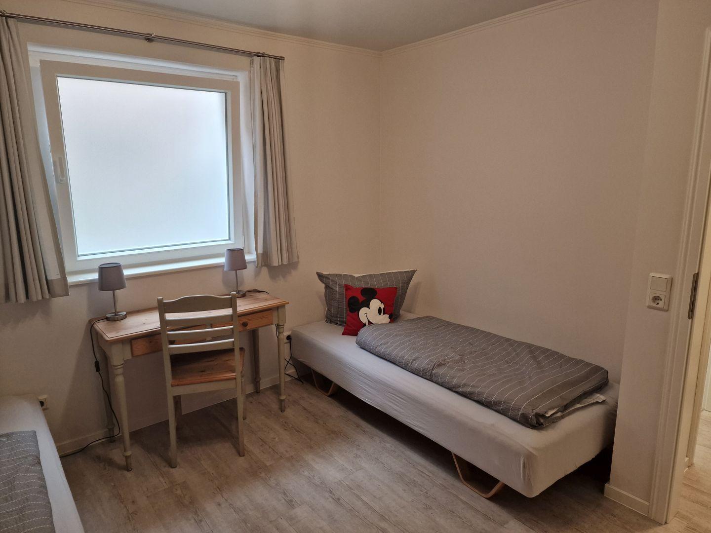 Ein Schlafzimmer mit einem Bett, einem Schreibtisch und einem Fenster.