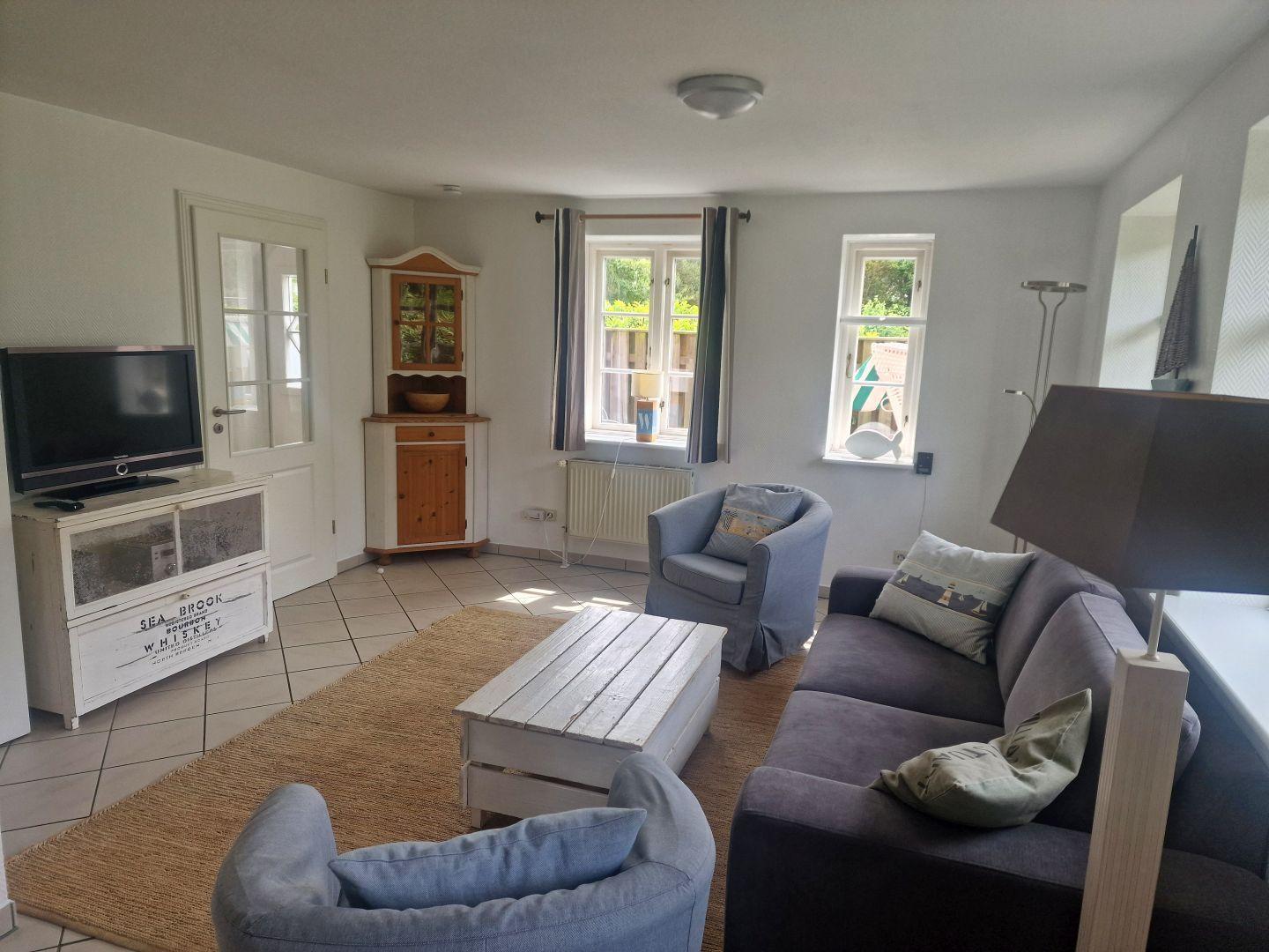 Wohnzimmer mit Sofa, Sessel, Couchtisch und Fernseher.