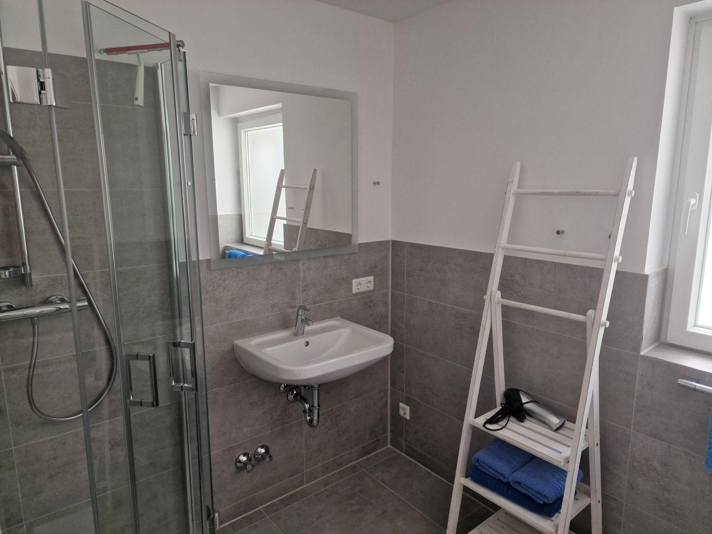 Badezimmer mit Dusche, Waschbecken und Fenster