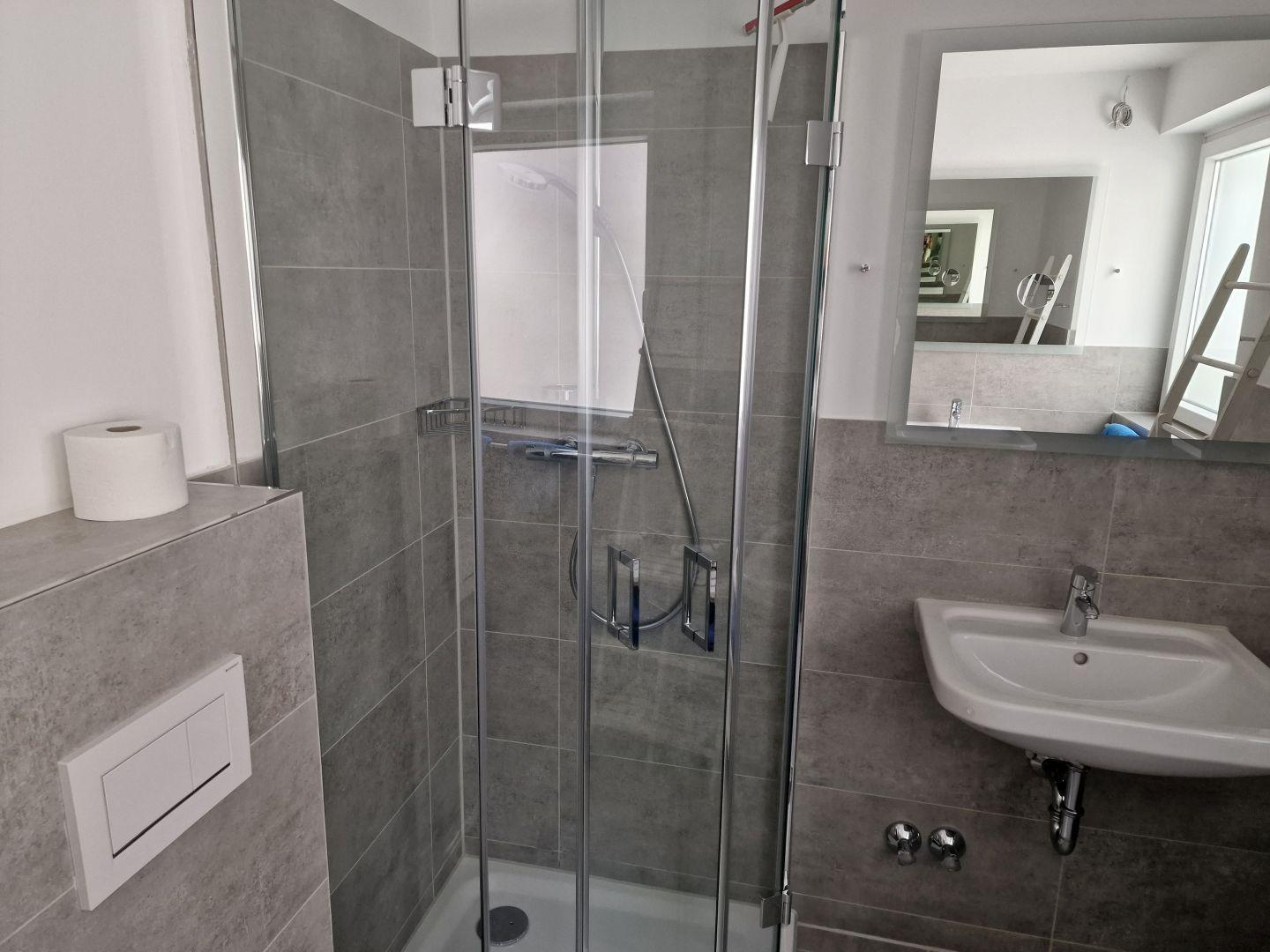 Bad mit Dusche, Waschbecken und Spiegel