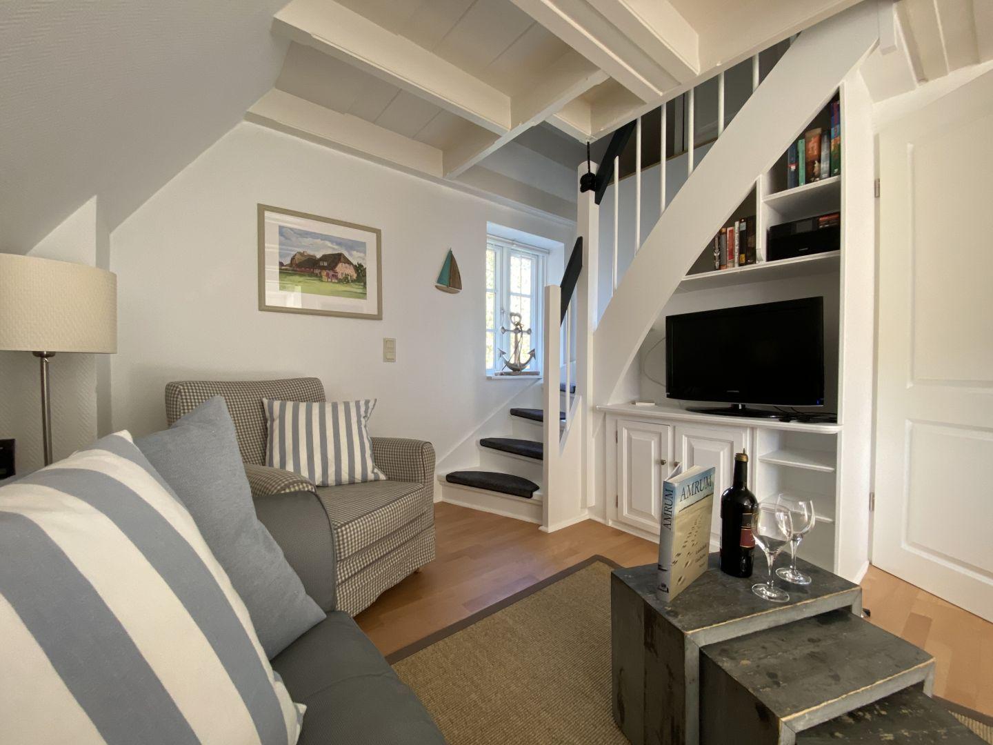 Wohnzimmer mit Sofa, Fernseher und Treppe zur oberen Etage.