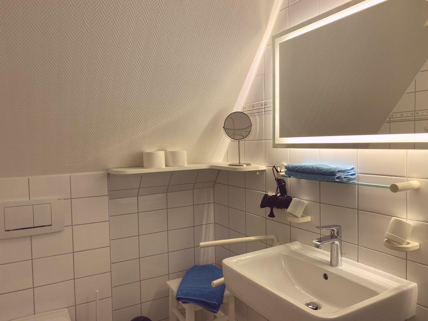 Badezimmer mit Waschbecken, Spiegel und Handtuchhalter.