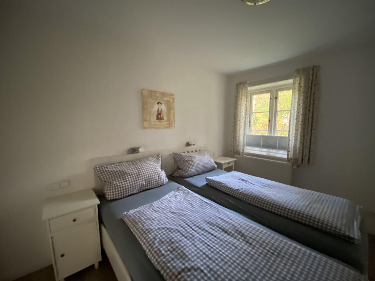 Zimmer mit zwei Betten, Fenster und Nachttisch