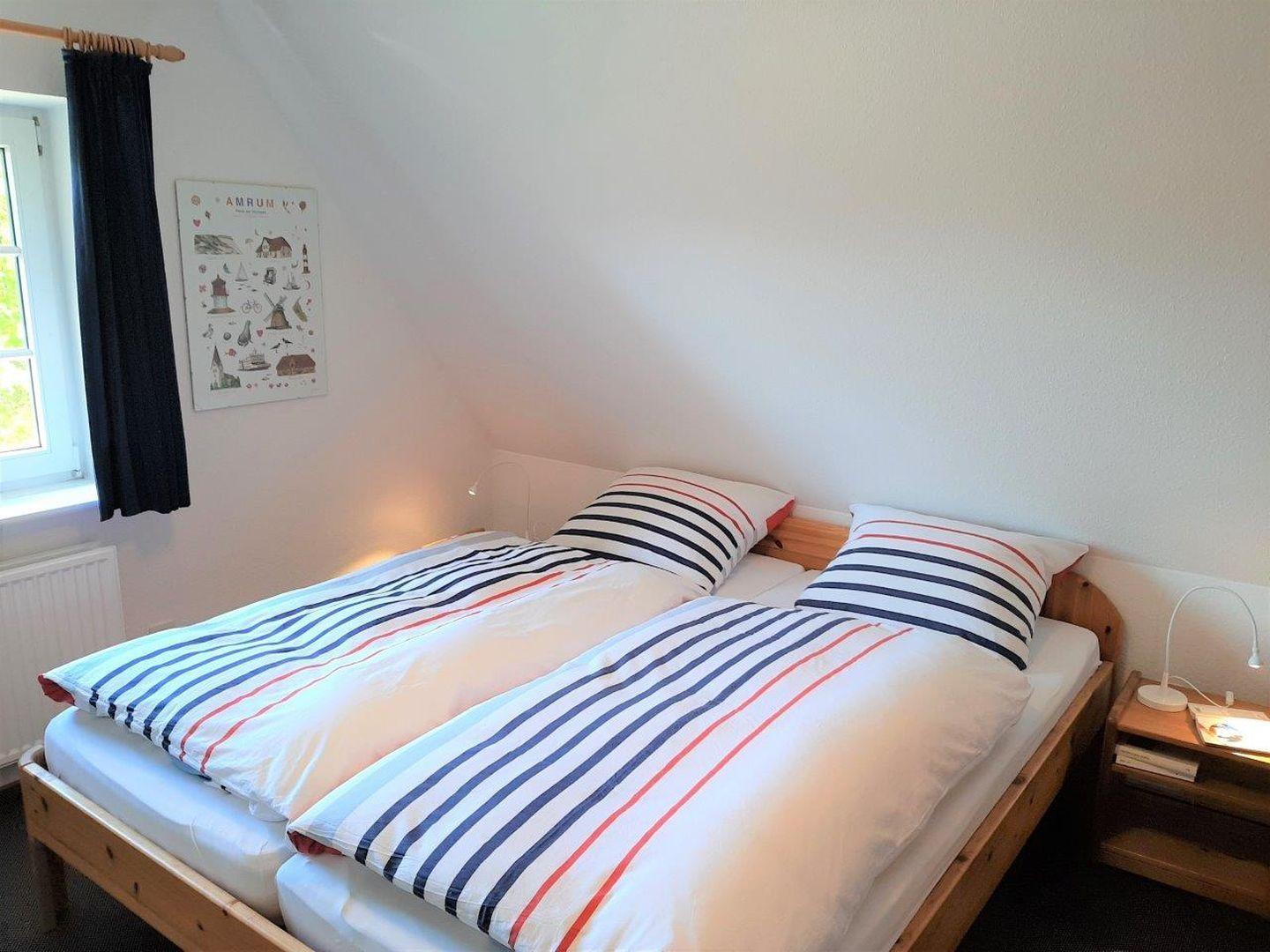 Zimmer mit Doppelbett, Fenster und Wandposter.