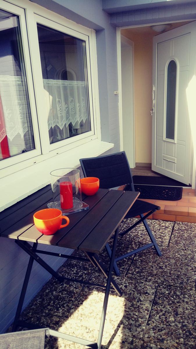 Terrasse mit Tisch, Stühlen und orangefarbenen Tassen.
