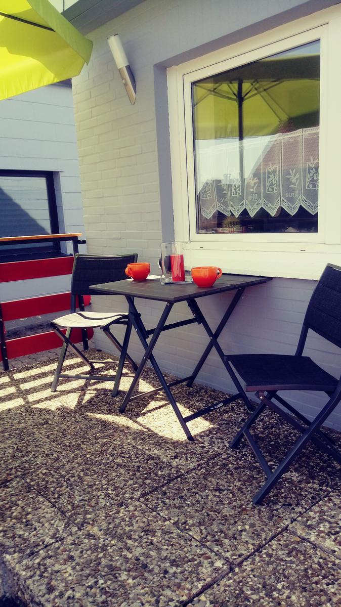 Außenbereich mit Tisch, Stühlen und gelbem Sonnenschirm.