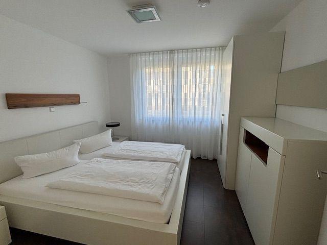 Bedroom with double bed, window with curtains, and closet.