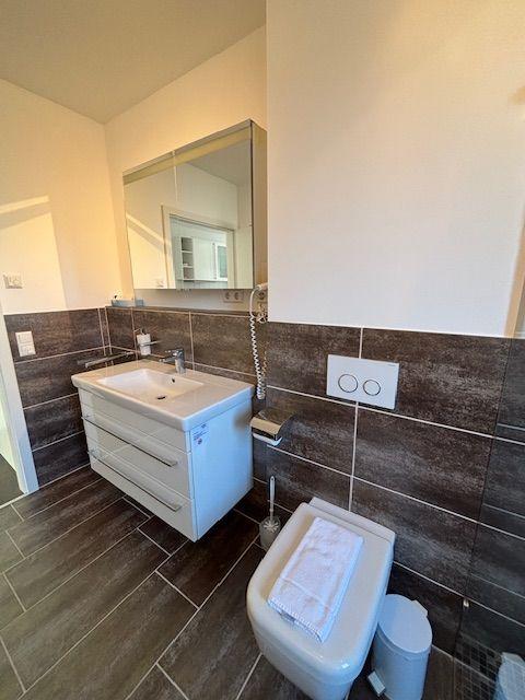 Bathroom with sink, mirror, and toilet. Tiled wall and floor.