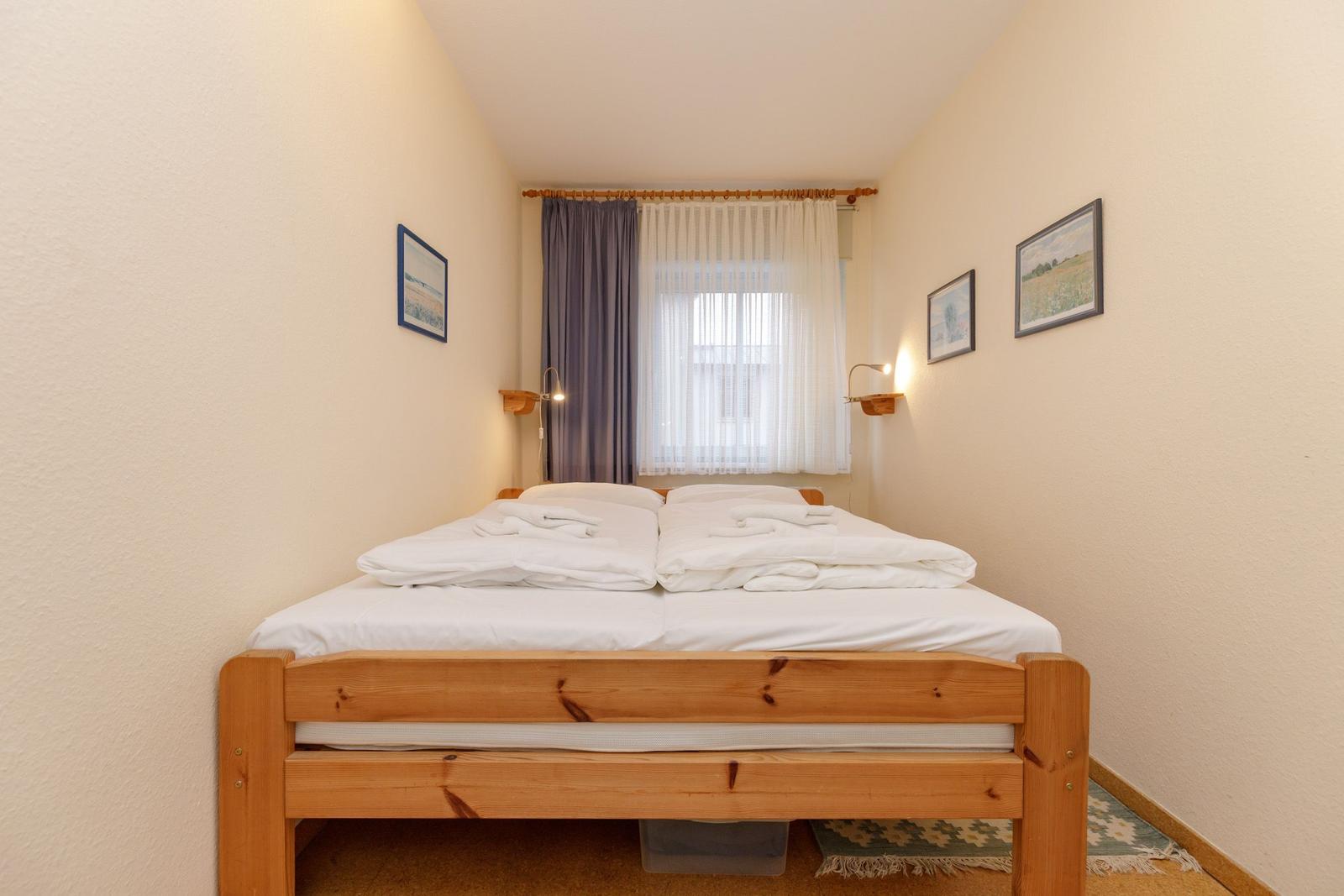 Ein Schlafzimmer mit einem Doppelbett, weißen Bettwäsche und einem Fenster mit Vorhängen.