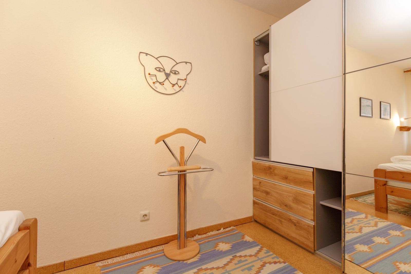 Schlafzimmer mit Kleiderständer, Schrank und Wanddekoration.