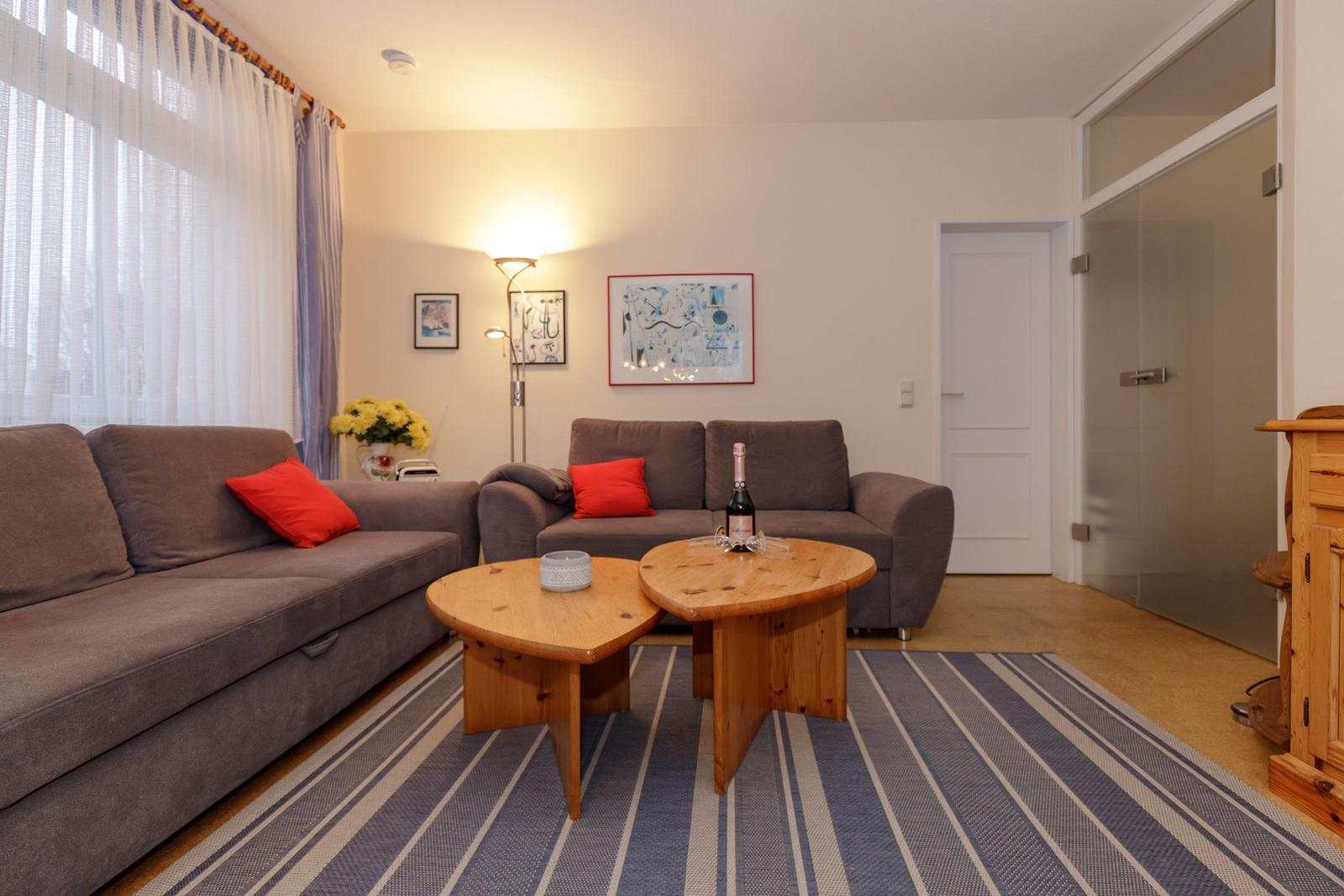 Wohnzimmer mit zwei Sofas, Holztisch und Blumen.