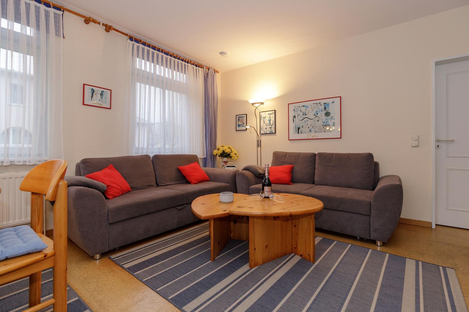 Wohnzimmer mit zwei grauen Sofas, Holztisch und Blumentopf.