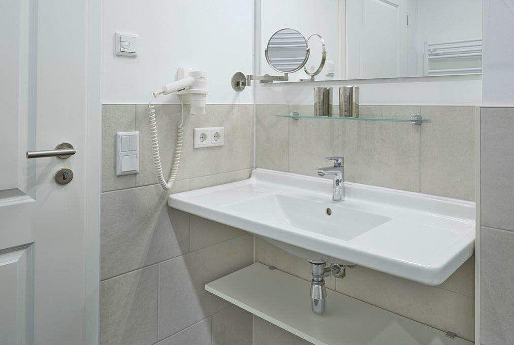 Badezimmer mit Waschbecken, Spiegel und Handtuchhalter.