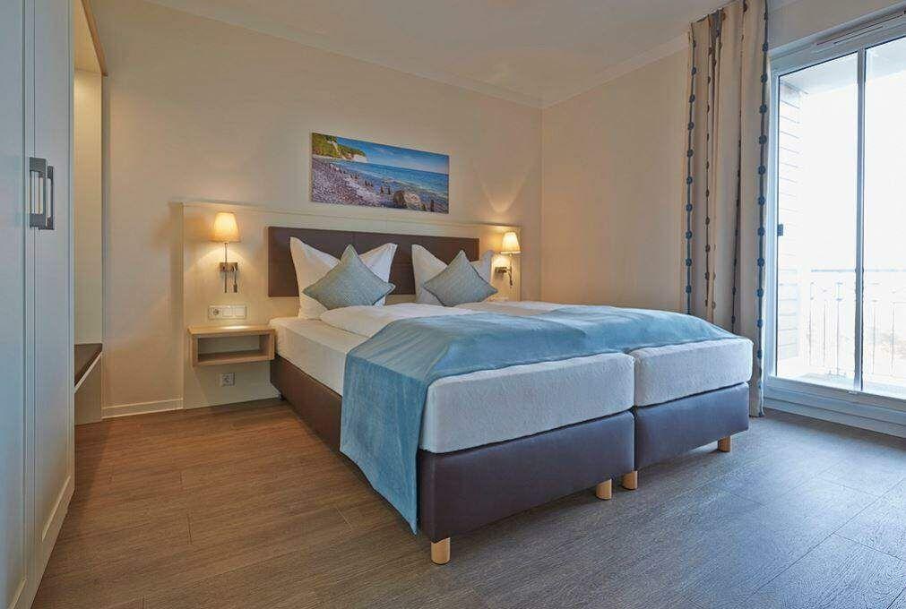 Schlafzimmer mit Doppelbett, Wandbild und Balkontür.