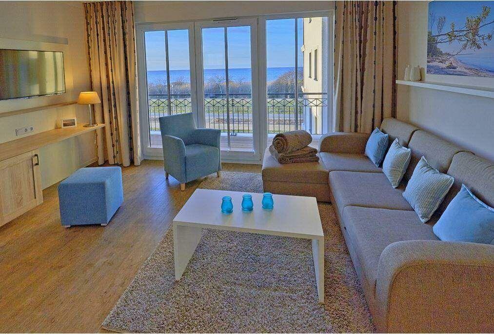 Wohnzimmer mit Sofa, Sessel und Balkonblick aufs Meer.
