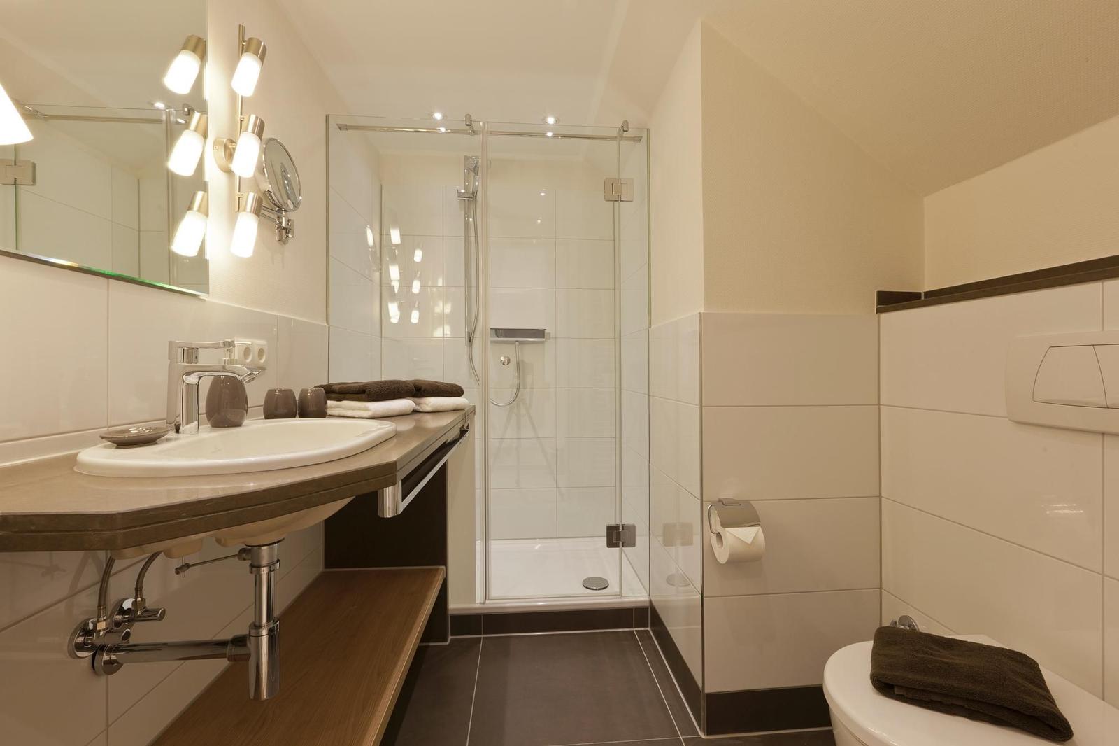 Badezimmer mit Dusche, Waschbecken und Toilette.