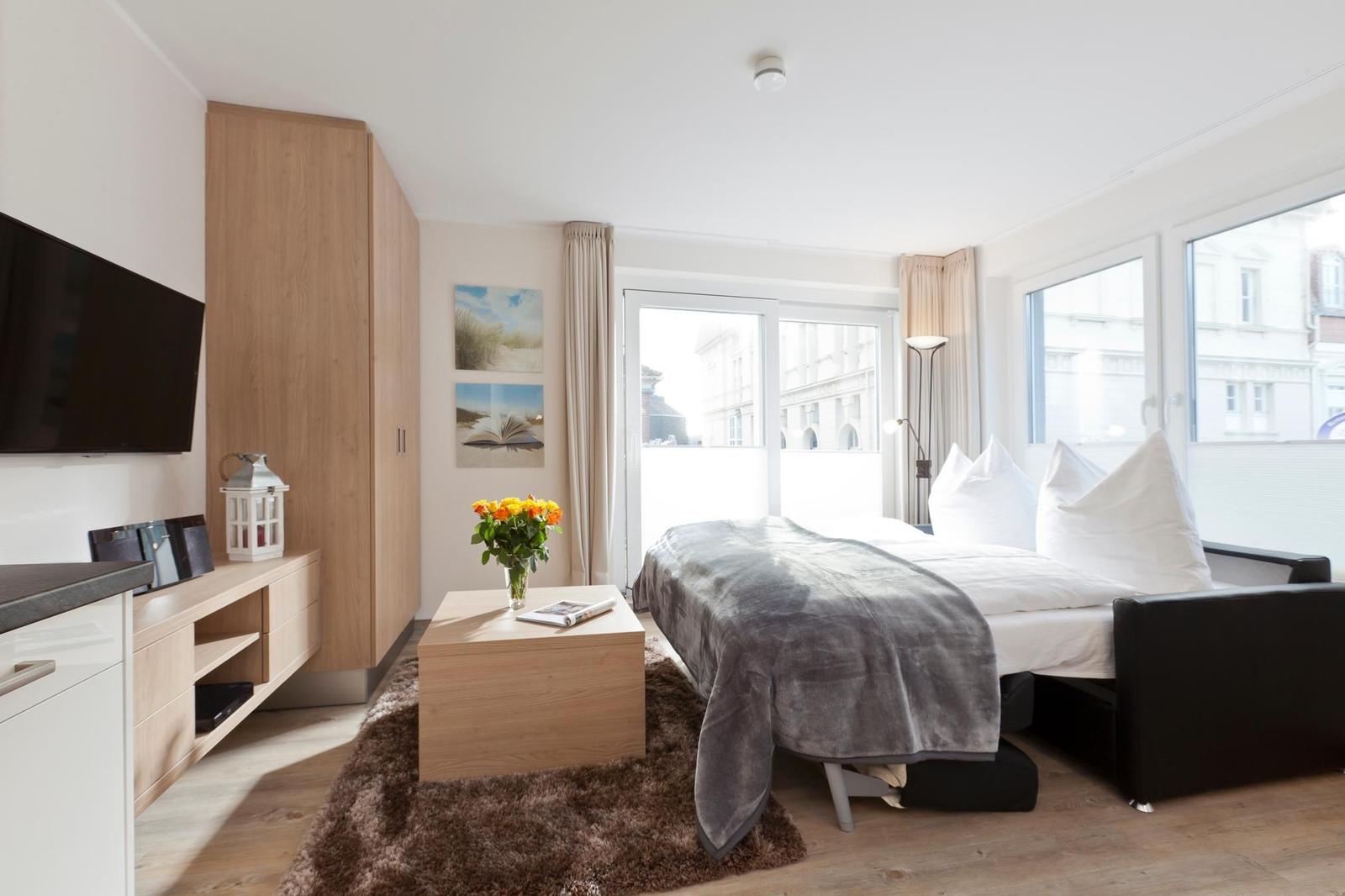Schlafzimmer mit Bett, TV und Fensterblick auf Gebäude