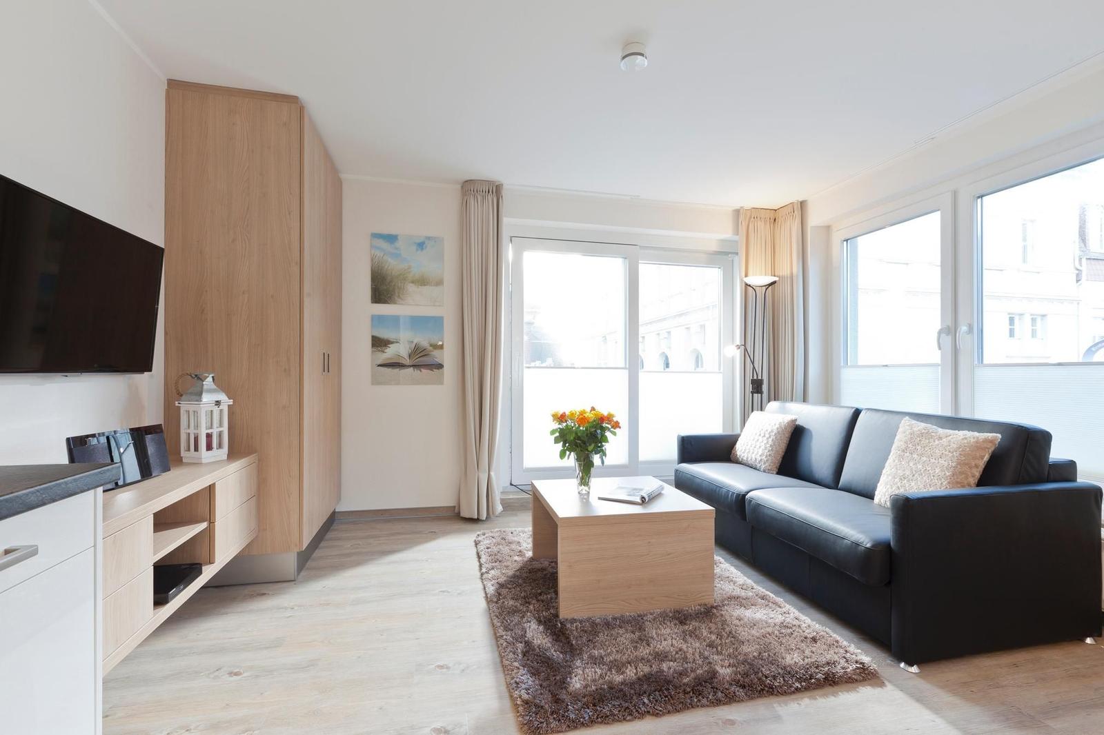 Wohnzimmer mit Sofa, Couchtisch und großen Fenstern.